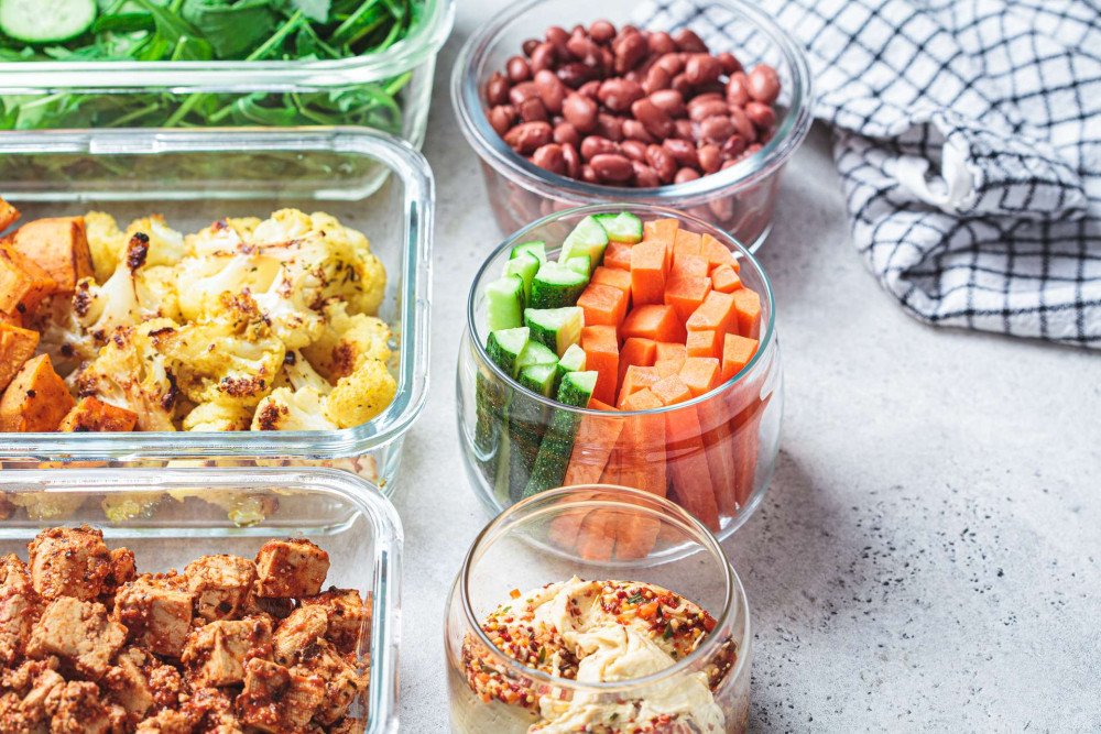 Vegan meal prep v sklenených dózach - tofu, karfiol, fazuľa a čerstvá zelenina